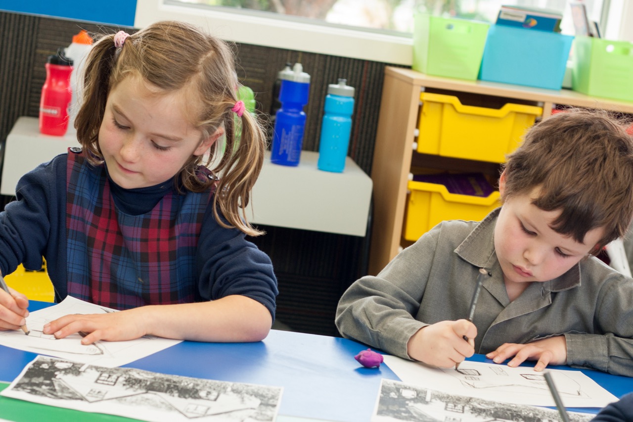Christ the King School students drawing and writing in the classroom