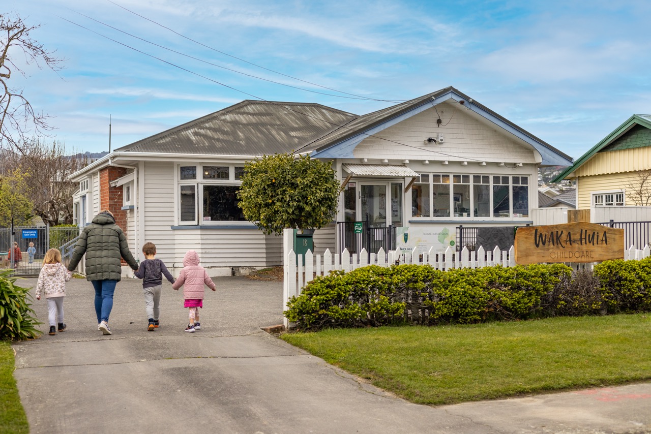 Two Waka Huia Childcare children holding coloured shapes up to their faces